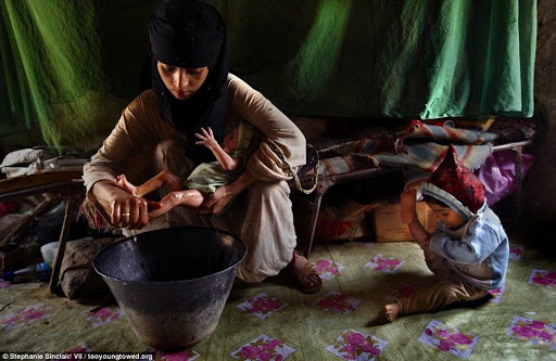 Child mothers: Asia, a 14-year-old mother, washes her new baby girl at home in Hajjah while her two-year-old daughter plays